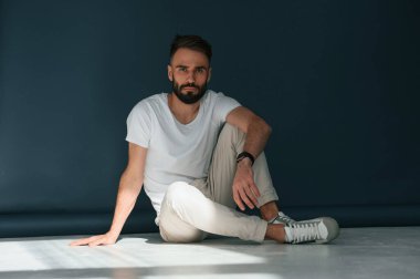 Yerde oturuyordum. Yakışıklı adam stüdyoda mavi arka planda..