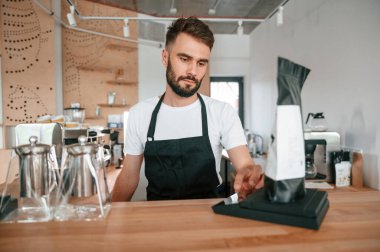 Paketin ağırlığını çiğ kahveyle ölçüyorum. Beyaz gömlekli ve siyah önlüklü kafe çalışanı içeride..