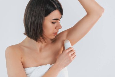 Top deodorantı kullanıyor. Genç esmer, beyaz arka planda..