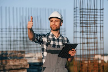 Başparmağımı gösteriyorum. Gündüz vakti inşaatta çalışan bir adam var..