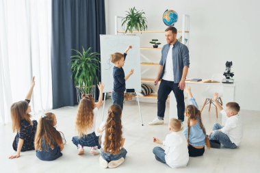 Tahtaya yazıyorum. Okulda öğretmenle birlikte bir grup çocuk öğrenci..