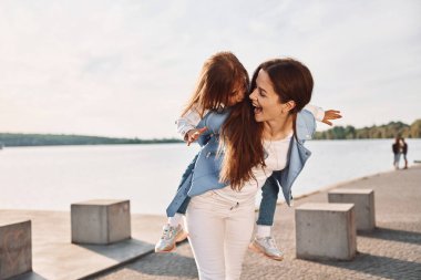Olumlu duygular. Genç anne ve kızı yazın göl kenarında eğleniyorlar..