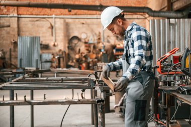 Profesyonel aletleri kullanarak. Üniformalı fabrika çalışanı içeride..