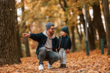 Babamın elinde bir şey var. Baba ve küçük oğlu gündüz vakti dışarıda beraberler..
