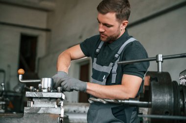 Parçaları geliştirmeye odaklanmış. Üniformalı adam iş yerinde tarım tekniğinin detaylarını geliştiriyor..