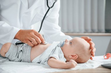 Manzarayı kapat. Steteskop kullanıyorum. Beyaz önlüklü doktor içeride küçük bebekle ilgileniyor..