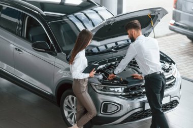 Kaput açıldı. Beyaz elbiseli bir adam araba galerisinde birlikte..