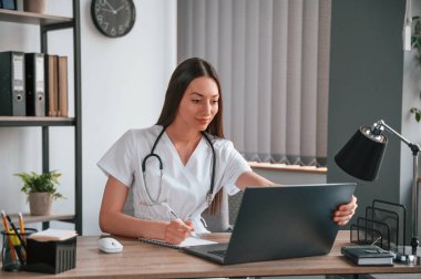 Online danışmanlık yapıyorum. Beyaz önlüklü güzel bayan doktor ofiste..