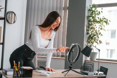 Akıllı telefonu kayıt için kuruyorum. Beyaz elbiseli genç ve güzel bayan ofiste..