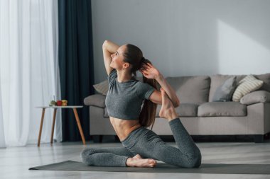 Eller uzanıyor. İnce vücutlu ve yoga elbiseli genç bir kadın evde..