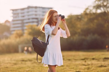 Profesyonel kamera ellerinde. Genç kız güneşli bir günde sahada güzel bir hafta sonu geçiriyor..