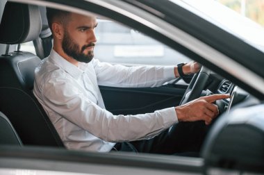 Test sürüşü. Beyaz elbiseli genç adam araba galerisinde..