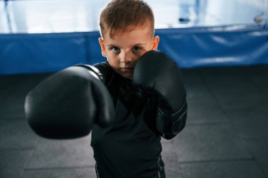 Çocuk ellerinde parıltılarla spor salonunda boks yapıyor..