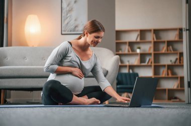 Laptop kullanarak yoga dersleri alıyorum. Güzel hamile kadın evde..