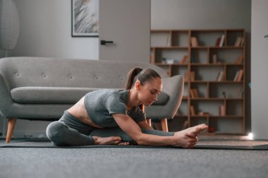 Yoga kıyafetleriyle. Esneme hareketleri yapıyorum. Genç bir kadın içeride spor yapıyor..