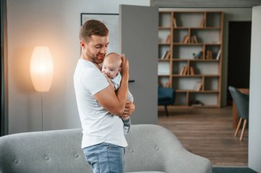 Elinde bebekle dikiliyorsun. Bebekli baba evde, oğluyla ilgileniyor..