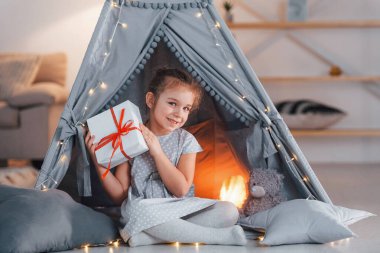 Hediye kutusunu tutuyorum. Evdeki çadırda oynayan sevimli küçük kız..
