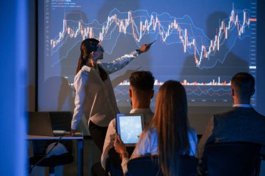 Planı projektörde gösteriyorum. Kadın lider borsa şirketinde çalışanlarla konuşuyor..