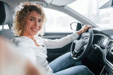 Yan görüş. Kıvırcık sarı saçlı kadın otosalonda..