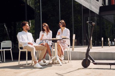 Sandalyelerde otururken. Üç arkadaş dışarıda harika bir hafta sonu geçiriyorlar..