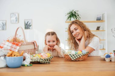 Gülümsüyor ve eğleniyor. Mutlu anne ve kız Paskalya tatillerini birlikte kutluyor..