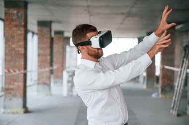 Eller yukarı! İnşaat alanında resmi kıyafetli bir adam VR oyunu oynuyor..