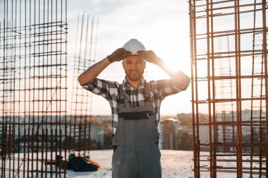 Güzel bir güneş ışığının altında dikiliyorum. Gündüz vakti inşaatta çalışan bir adam var..