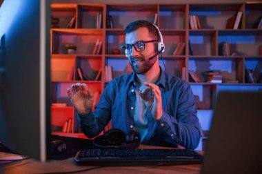 Okuma ve mavi neon ışıkları. Adam evde bilgisayarın başında oturuyor..