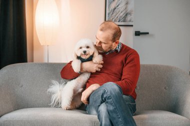 Adam evde, kanepede köpeğiyle oturuyor..