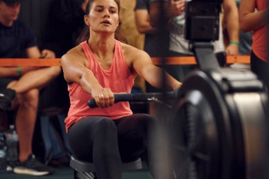 Ön manzara. Spor salonunda kürek çeken sporcu bir kadın..