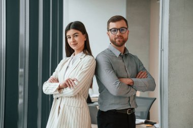 Kadın ve erkek ayakta duruyor ve poz veriyor. Ofiste başarılı bir ekip birlikte çalışıyor. İş kavramı.