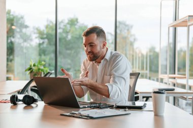 Başarılı bir proje. Kutlama ve mutluluk kavramı. Resmi kıyafetli adam modern ofiste çalışıyor..