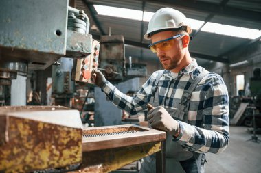Fabrika makinesiyle çalışmaya odaklanmış. Üniformalı işçi içeride..