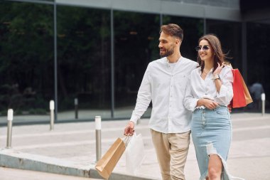 Modern binanın yanında yürüyorum. Güzel bir çift gün içinde dışarıda alışveriş yapar..