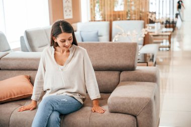 Oturup dinleniyorum. Kadın yatak mağazasını ziyaret ediyor. Rahat bir kanepe arıyorum..