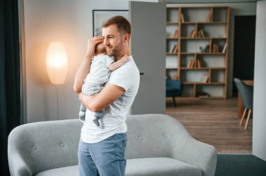 Bebeği ellerimde tutuyorum. Bebekli baba evde, oğluyla ilgileniyor..