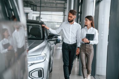 Otomobil yüzeyine dokunmak. Beyaz elbiseli bir adam araba galerisinde birlikte..