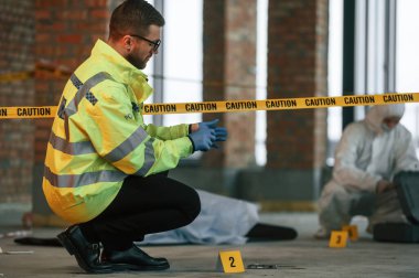 Yerde bir ceset var. Dedektifler suç mahallinde kanıt topluyorlar..