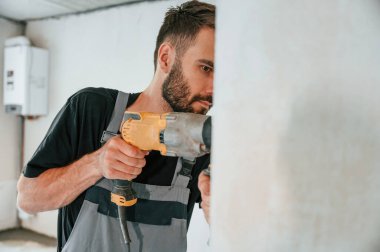 Duvarda delik açmak. Adam dairede tamirat yapıyor..