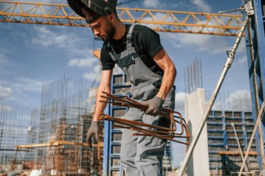 Paslı metal parçalarıyla çalışıyorum. Üniformalı adam şantiyede..