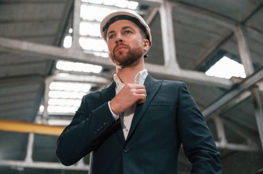 Yakayı düzeltir. Fabrikada resmi siyah giyim müdürü..