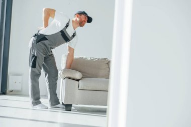 Ağır kanepe. Omurga acıyor. Tamirci modern odada kapalı alanda çalışıyor..