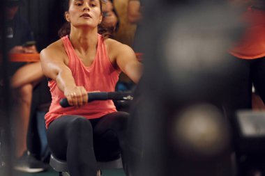 Ön manzara. Spor salonunda kürek çeken sporcu bir kadın..