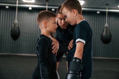 Dövüş öncesi hazırlık. Birbirlerine bakıyorlar. Genç dövmeli koç çocuklara boks teknikleri öğretiyor..