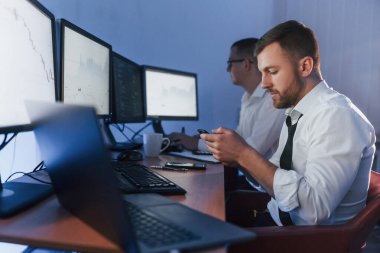 Masada bir sürü ekran var. Ofiste değişim teknolojisiyle çalışan iki borsacı..
