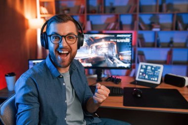 Zaferi kutluyoruz. Adam bilgisayarında nişancı oyunu oynuyor. Neon ışıkları.