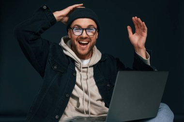 Başarıyı kutluyoruz. Neşelendirici hissediyorum. Laptop kullanıyorum. Yakışıklı adam stüdyoda arka planda..