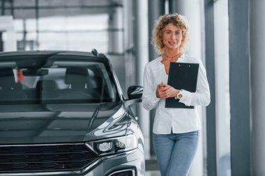 Not defterini tutuyorum. Kıvırcık sarı saçlı kadın otosalonda..