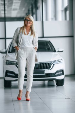 Durup poz vermek. Beyaz elbiseli kadın araba galerisinde..