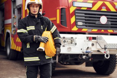 Dışarıda, kamyonun yanında ve ellerinde yangın hortumuyla. Üniformalı kadın departmanda çalışıyor..